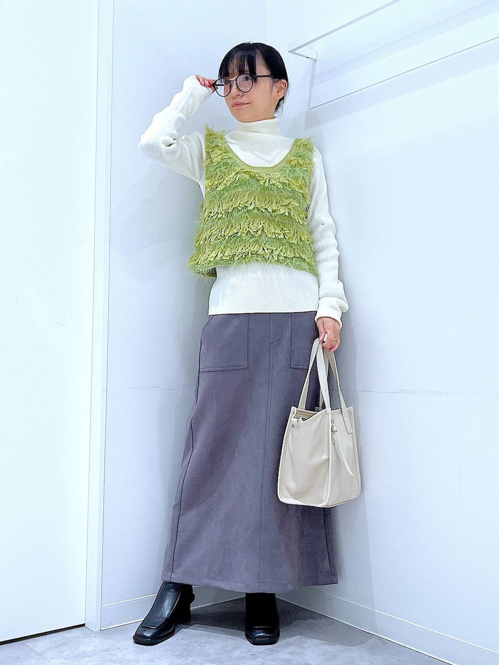 ブラック系のブーツ、グレー系のスカート、ベージュ系のニット/セーターを着用したレディースの冬コーディネートの2枚目の写真