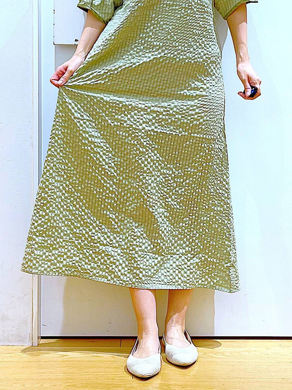 グリーン系のワンピース、ホワイト系のパンプス、ブラック系のハンドバッグを着用したレディースの春コーディネートの8枚目の写真