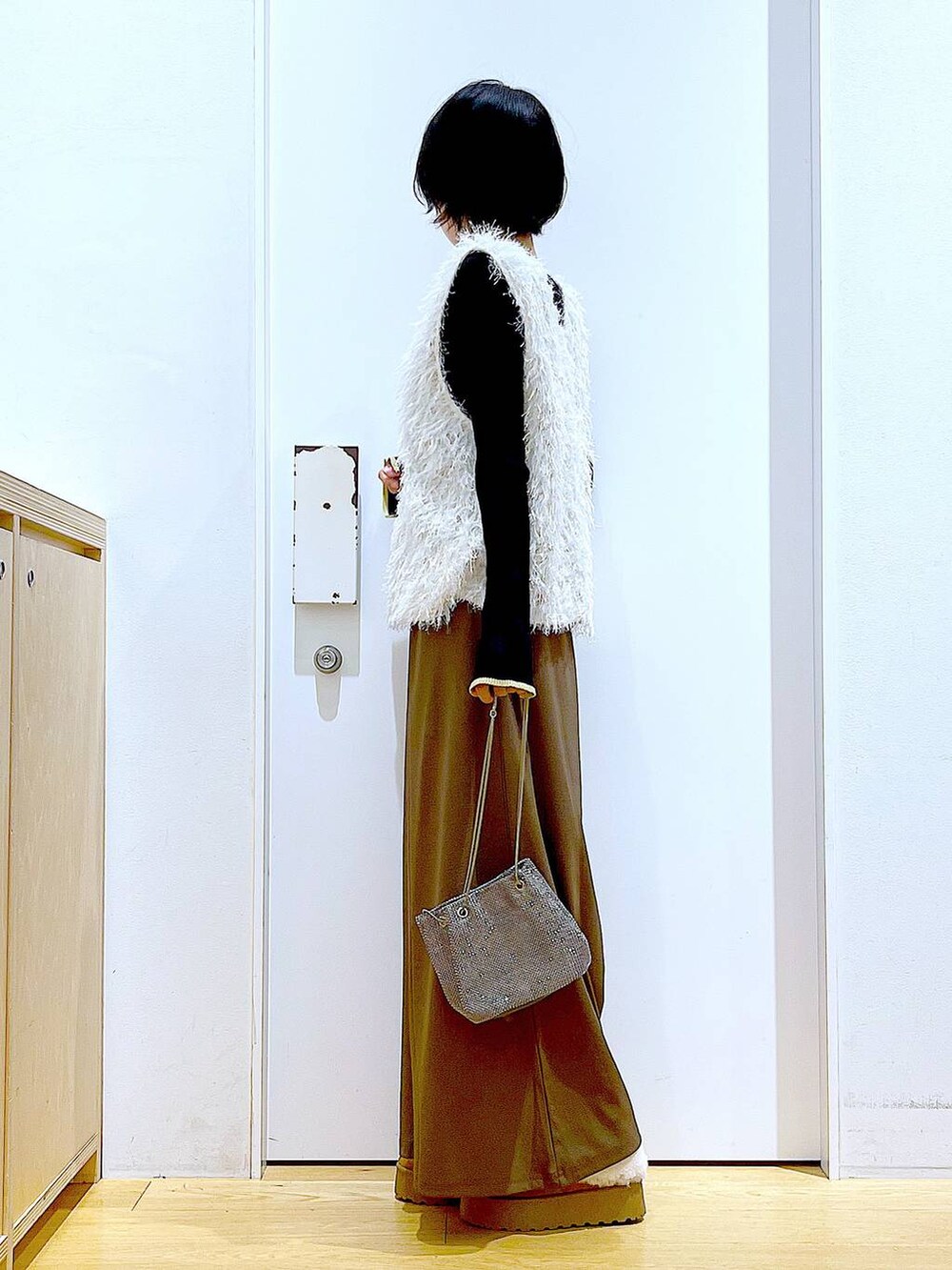 ブラック系のニット/セーター、グレー系のショルダーバッグ、ベージュ系のベストを着用したレディースの秋コーディネートの3枚目の写真