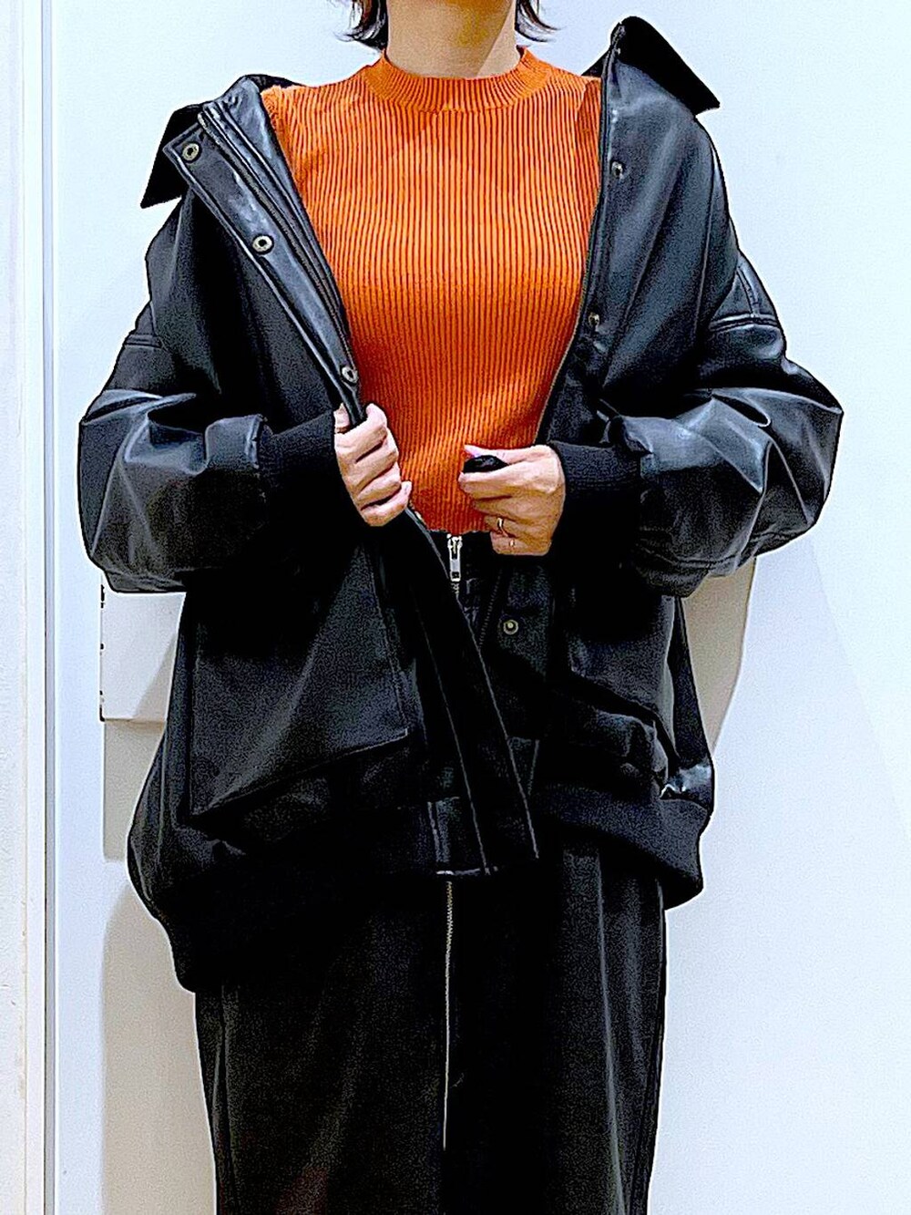 オレンジ系のニット/セーター、ブラウン系のスカート、ブラック系のブーツを着用したレディースの冬コーディネートの7枚目の写真