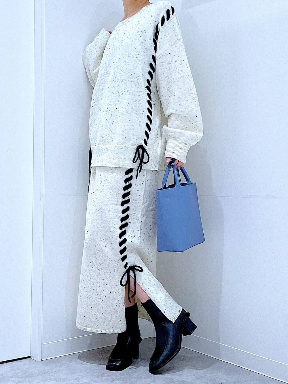 ブルー系のショルダーバッグ、ホワイト系のニット/セーター、ベージュ系のスカートを着用したレディースの秋コーディネートの6枚目の写真