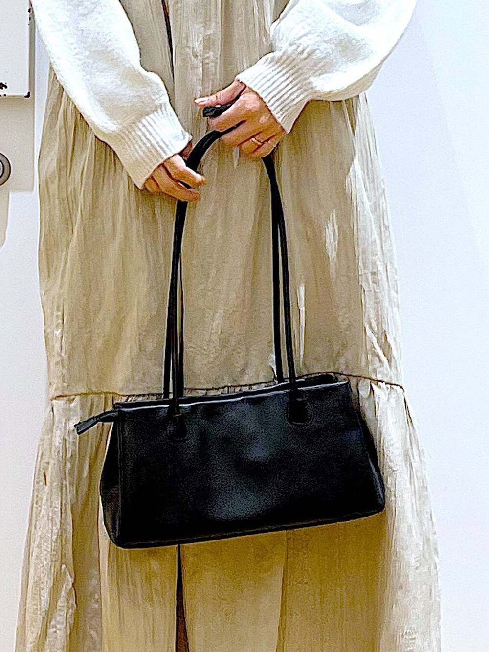 ブラック系のブーツ、ブラック系のトートバッグ、ベージュ系のニット/セーターを着用したレディースの冬コーディネートの9枚目の写真