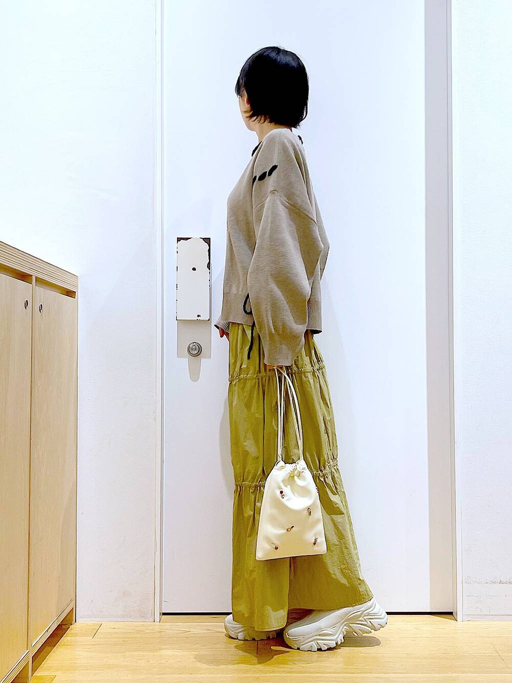 ホワイト系のショルダーバッグ、イエロー系のスカート、ベージュ系のブーツを着用したレディースの秋コーディネートの3枚目の写真