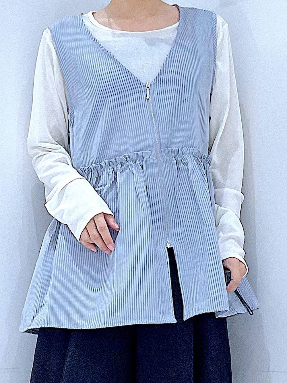 ブラック系のスラックス、ブルー系のベスト、ホワイト系のTシャツ/カットソーを着用したレディースの秋コーディネートの7枚目の写真