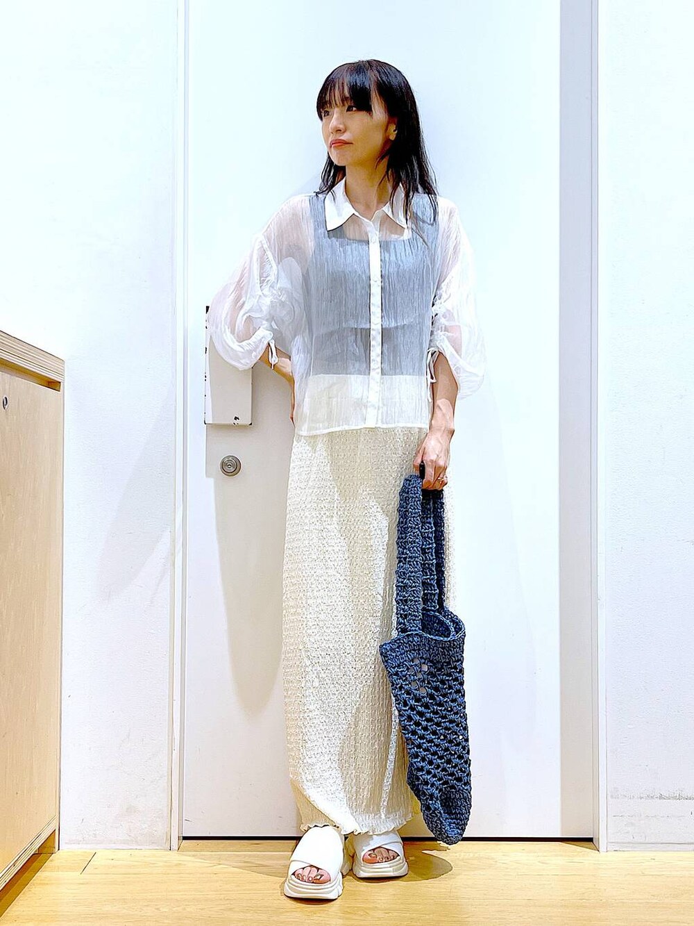 ホワイト系のサンダル、ブラック系のニット/セーター、ブルー系のトートバッグを着用したレディースの夏コーディネートの2枚目の写真