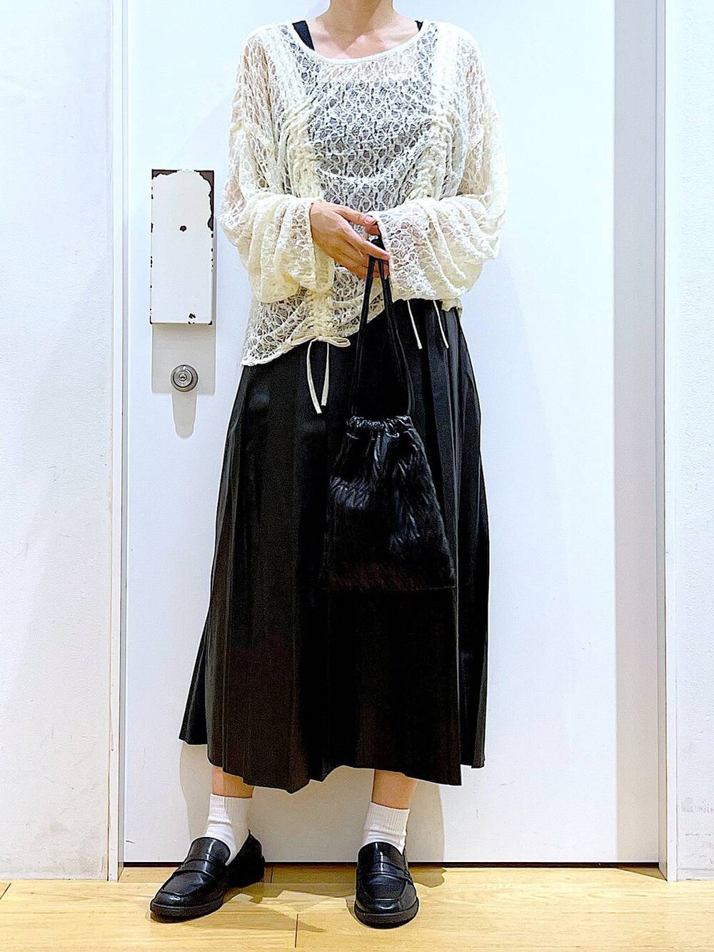 ブラック系のショルダーバッグ、ブラック系のローファー、ベージュ系のTシャツ/カットソーを着用したレディースの秋コーディネートの6枚目の写真