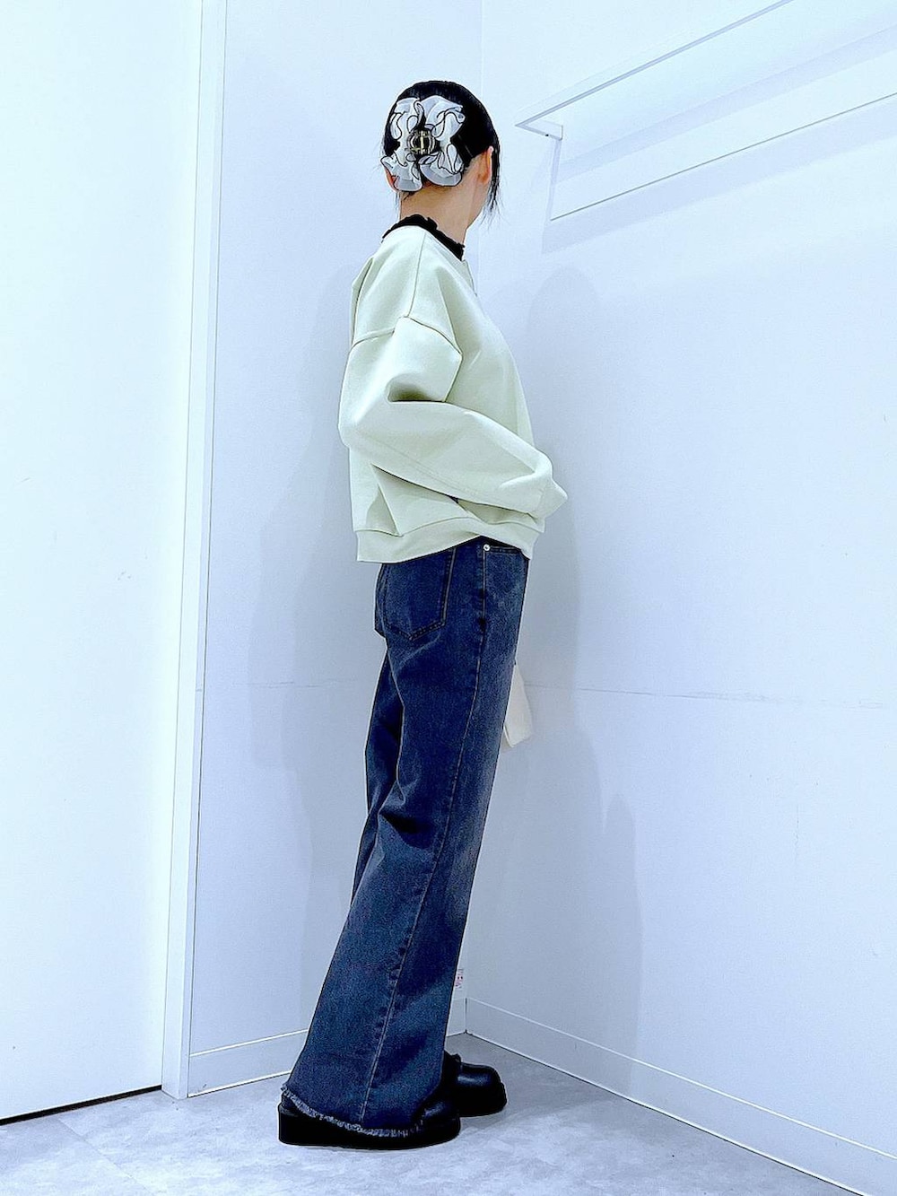 ホワイト系のショルダーバッグ、グリーン系のスウェット、ブラック系のデニムパンツを着用したレディースの春コーディネートの4枚目の写真