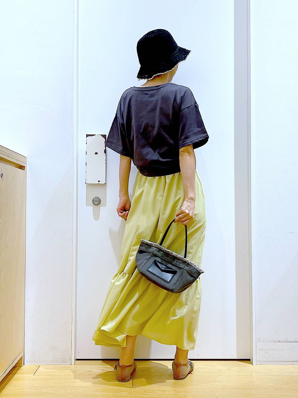 ブラック系のショルダーバッグ、ベージュ系のパンプス、イエロー系のワンピースを着用したレディースの春コーディネートの5枚目の写真