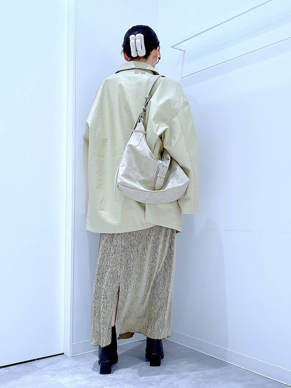 ベージュ系のステンカラーコート、ブラック系のブーツ、ホワイト系のショルダーバッグを着用したレディースの冬コーディネートの5枚目の写真