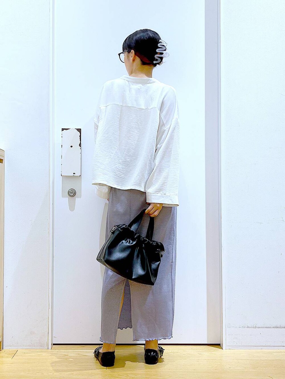 パープル系のスカート、ブラック系のショルダーバッグ、ブラック系のパンプスを着用したレディースの秋コーディネートの5枚目の写真