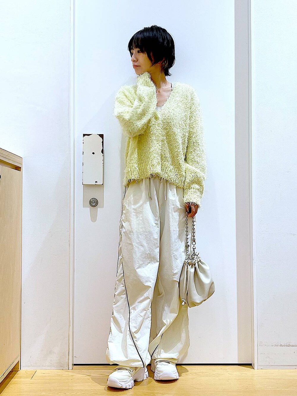 ベージュ系のショルダーバッグ、ホワイト系のスニーカー、イエロー系のカーディガン/ボレロを着用したレディースの秋コーディネートの2枚目の写真