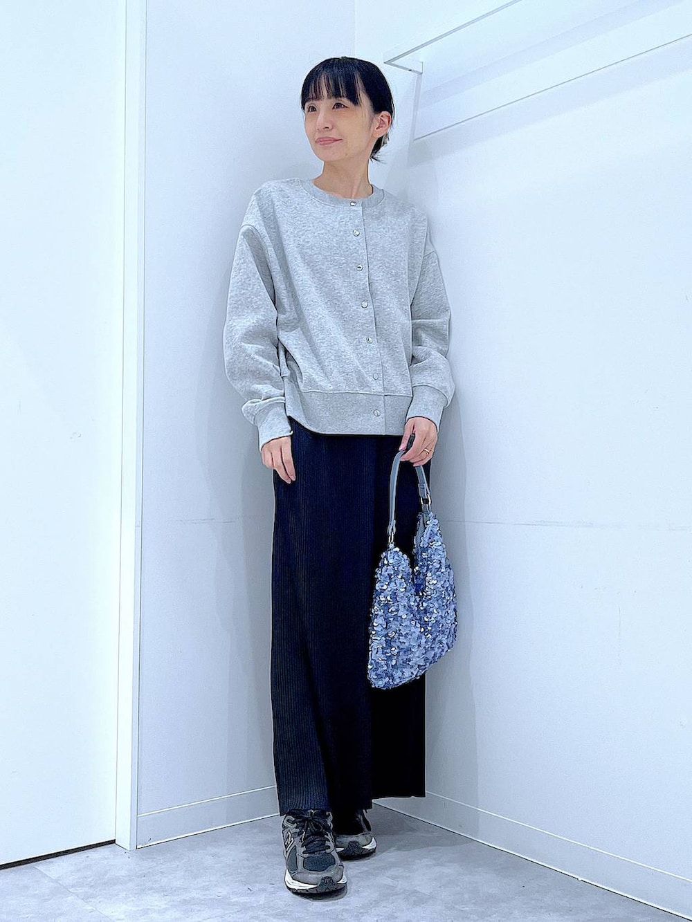 グレー系のカーディガン/ボレロ、ブルー系のショルダーバッグ、ブラック系のスカートを着用したレディースの春コーディネートの2枚目の写真