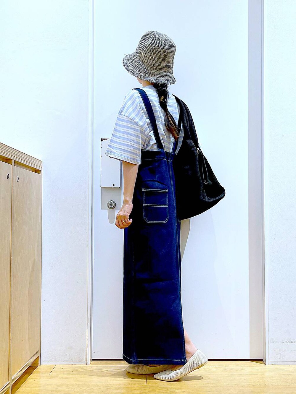 ホワイト系のパンプス、ブルー系のジャンパースカート、ブラック系のショルダーバッグを着用したレディースの夏コーディネートの3枚目の写真