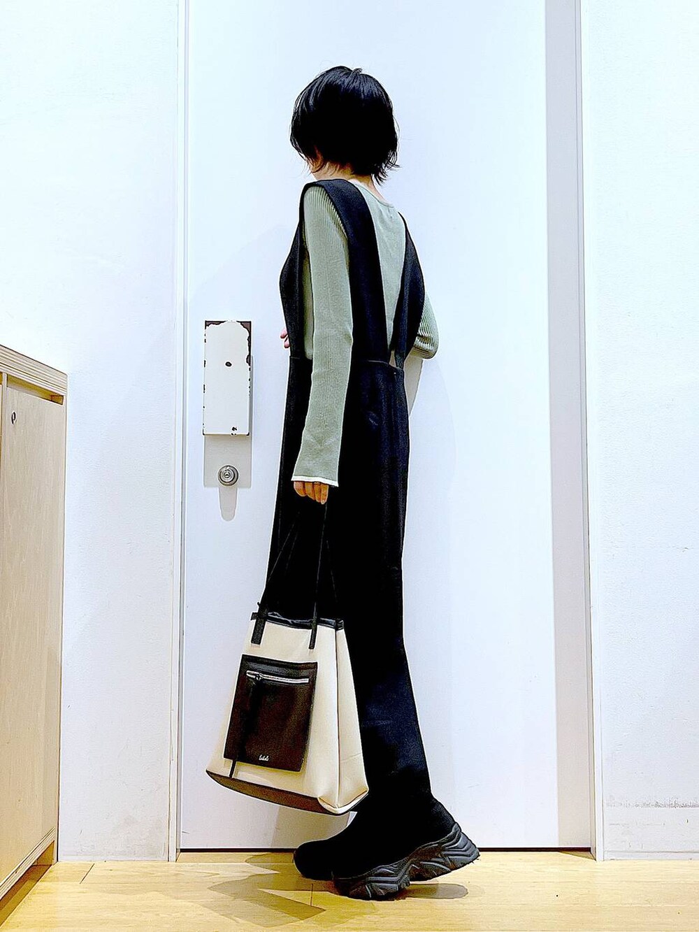 グリーン系のニット/セーター、ブラック系のブーツ、ブラック系のサロペット/オーバーオールを着用したレディースの冬コーディネートの3枚目の写真