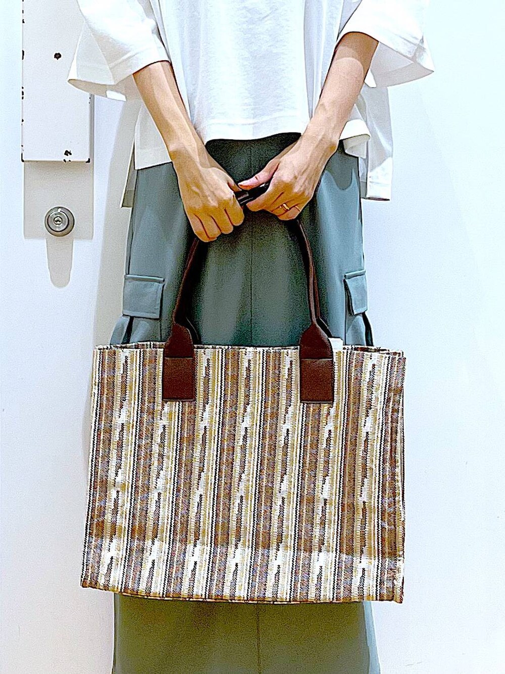 ホワイト系のサンダル、グリーン系のスカート、ブラウン系のトートバッグを着用したレディースの夏コーディネートの9枚目の写真
