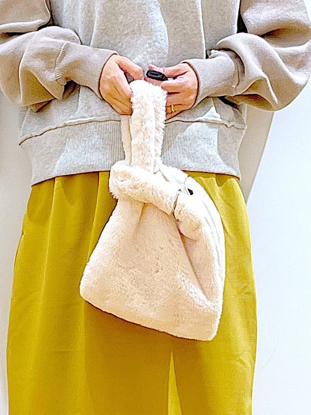 ホワイト系のショルダーバッグ、ブラック系のブーツ、ベージュ系のニット/セーターを着用したレディースの冬コーディネートの9枚目の写真