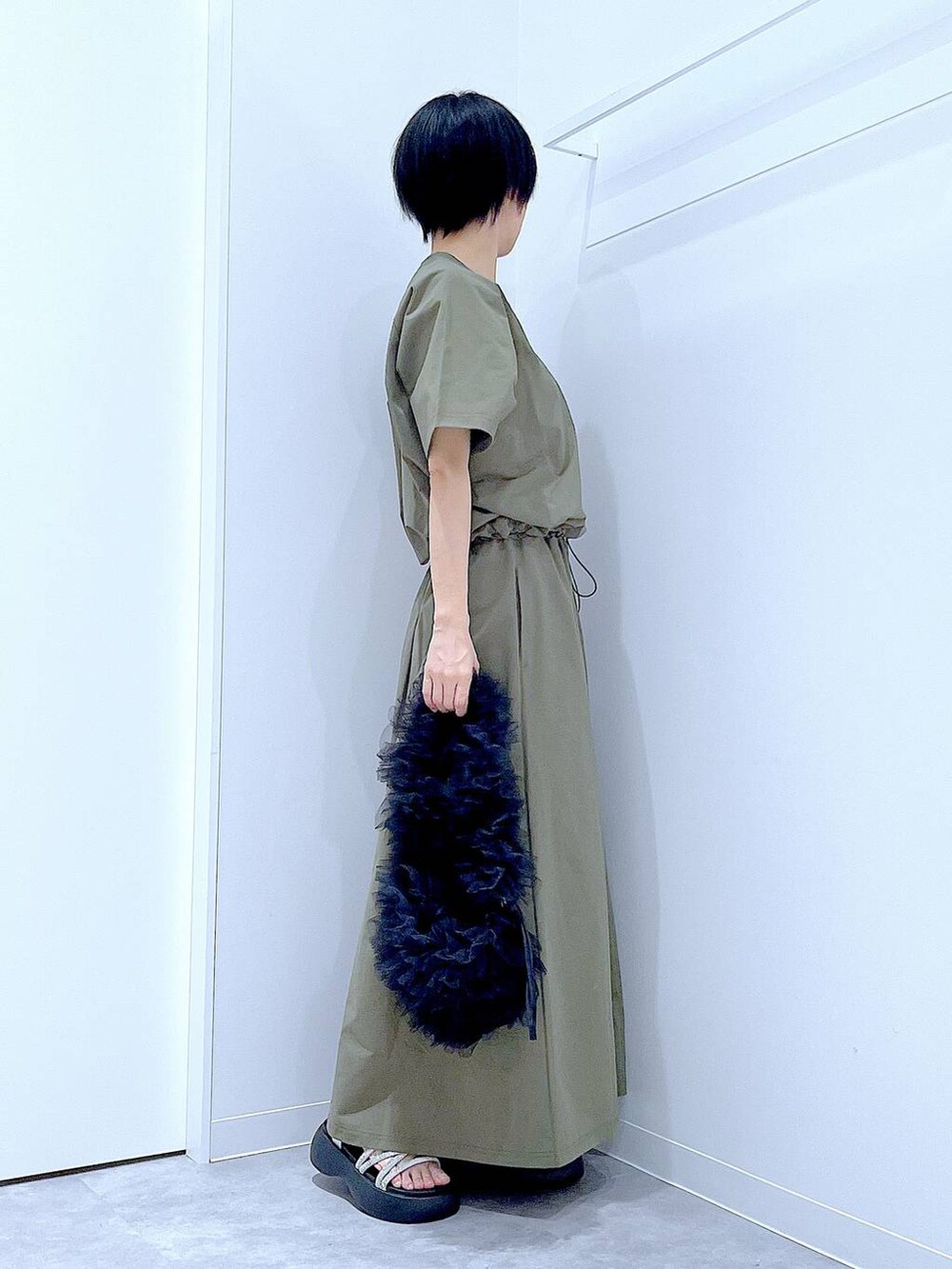 ブラック系のショルダーバッグ、シルバー系のサンダル、グリーン系のTシャツ/カットソーを着用したレディースの夏コーディネートの4枚目の写真