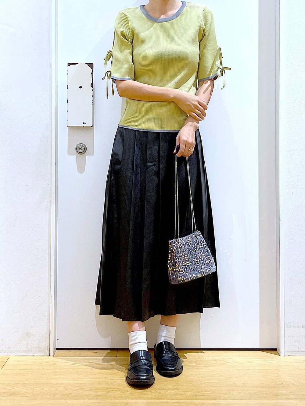 グレー系のショルダーバッグ、ブラック系のローファー、イエロー系のニット/セーターを着用したレディースの秋コーディネートの6枚目の写真