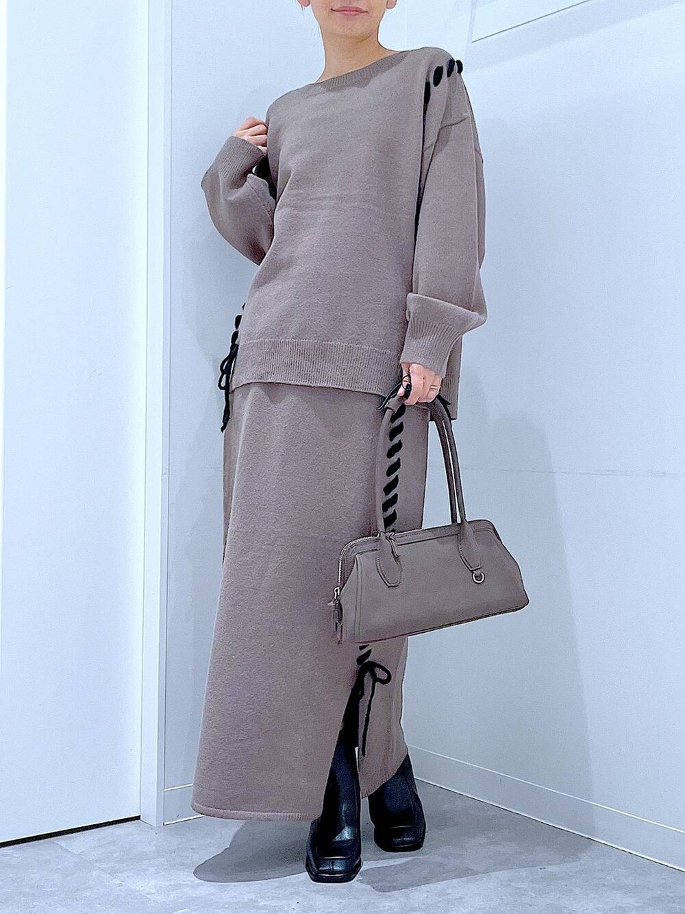 ブラウン系のニット/セーター、ブラウン系のスカート、ブラック系のブーツを着用したレディースの秋コーディネートの6枚目の写真