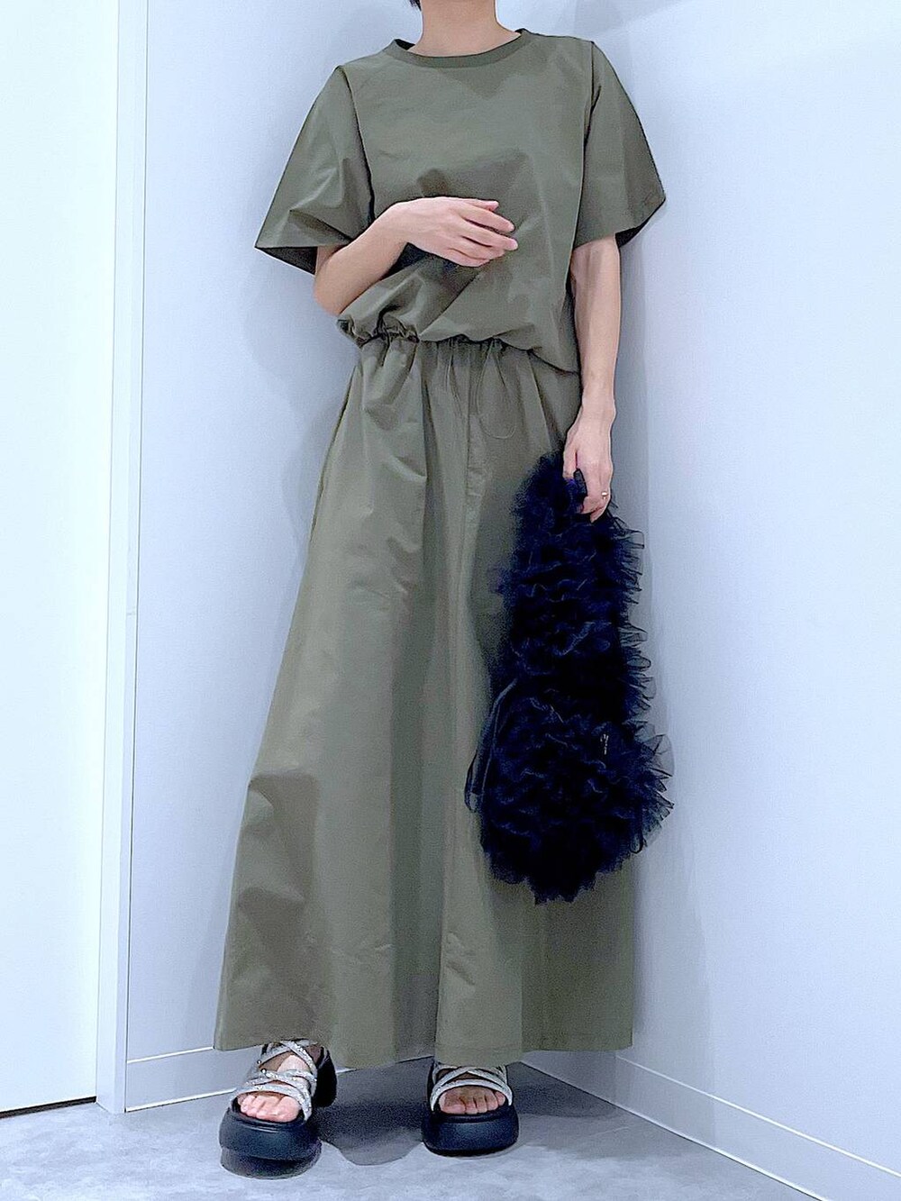 ブラック系のショルダーバッグ、シルバー系のサンダル、グリーン系のTシャツ/カットソーを着用したレディースの夏コーディネートの6枚目の写真