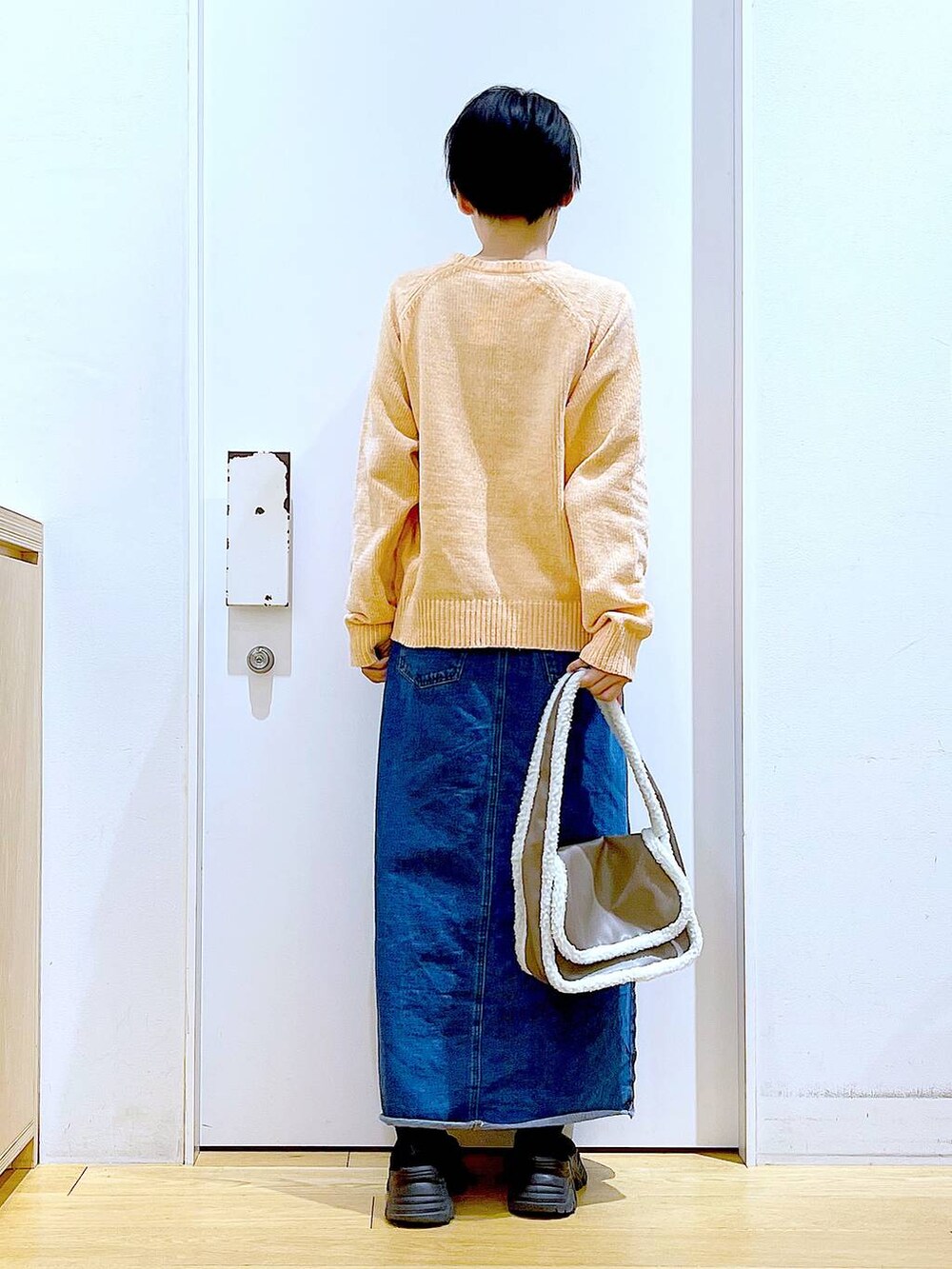 ブルー系のデニムスカート、ベージュ系のショルダーバッグ、ブラック系のブーツを着用したレディースの冬コーディネートの5枚目の写真