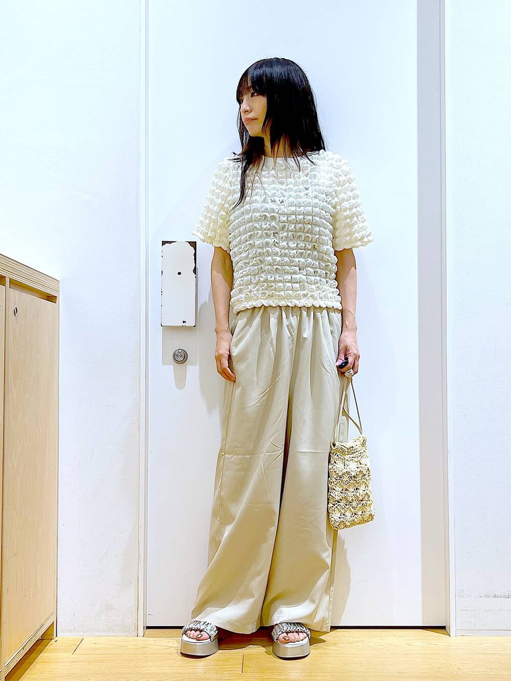 シルバー系のサンダル、ベージュ系のショルダーバッグ、ベージュ系のTシャツ/カットソーを着用したレディースの夏コーディネートの2枚目の写真