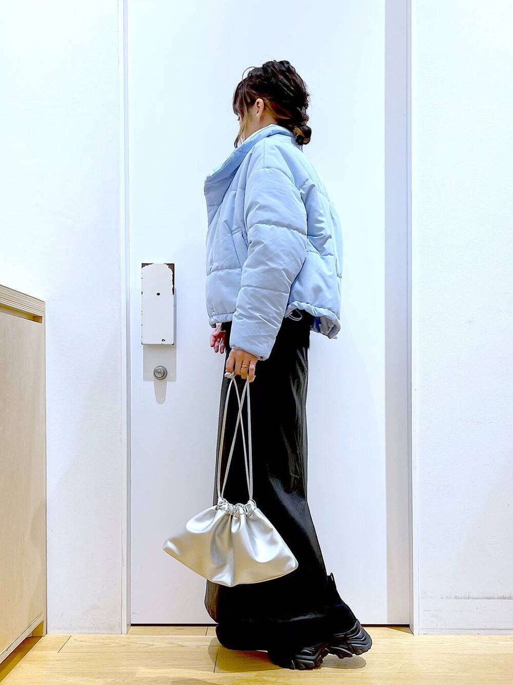 ブラック系のブーツ、シルバー系のショルダーバッグ、ブルー系のナイロンジャケットを着用したレディースの冬コーディネートの3枚目の写真