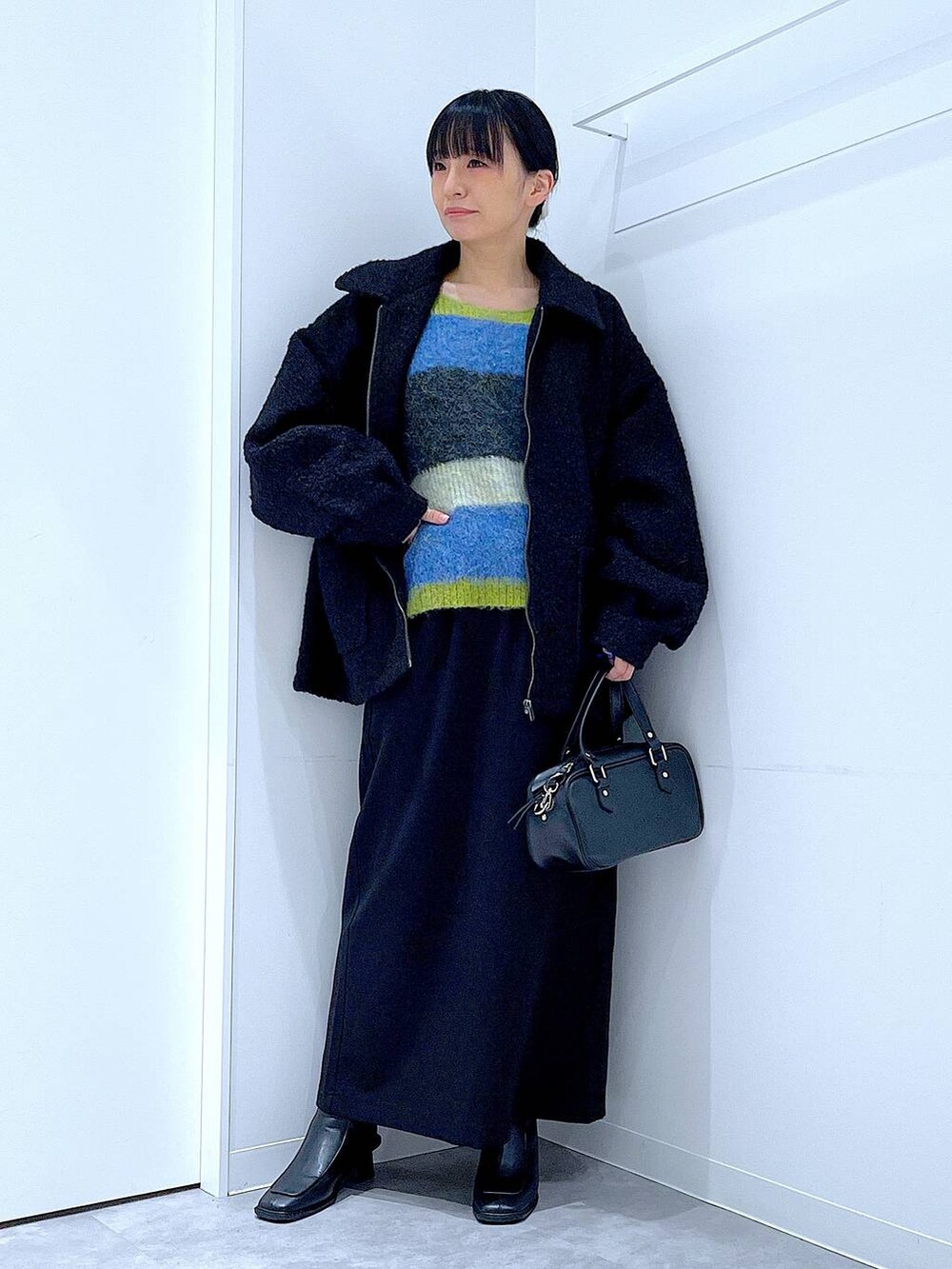 ブラック系のスカート、ブラック系のブルゾン、ブラック系のブーツを着用したレディースの冬コーディネートの2枚目の写真