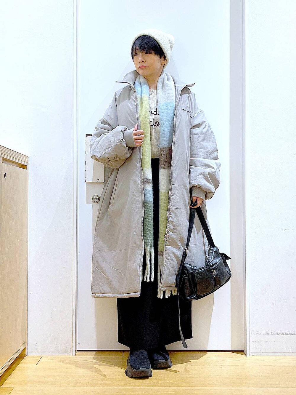 グレー系のミリタリージャケット、ブラック系のブーツ、ブラック系のショルダーバッグを着用したレディースの冬コーディネートの2枚目の写真