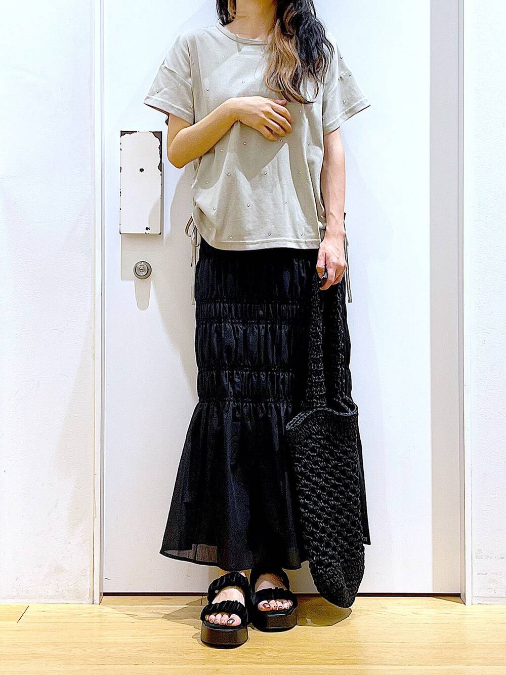 ブラック系のサンダル、ブラック系のスカート、ブラック系のトートバッグを着用したレディースの夏コーディネートの6枚目の写真