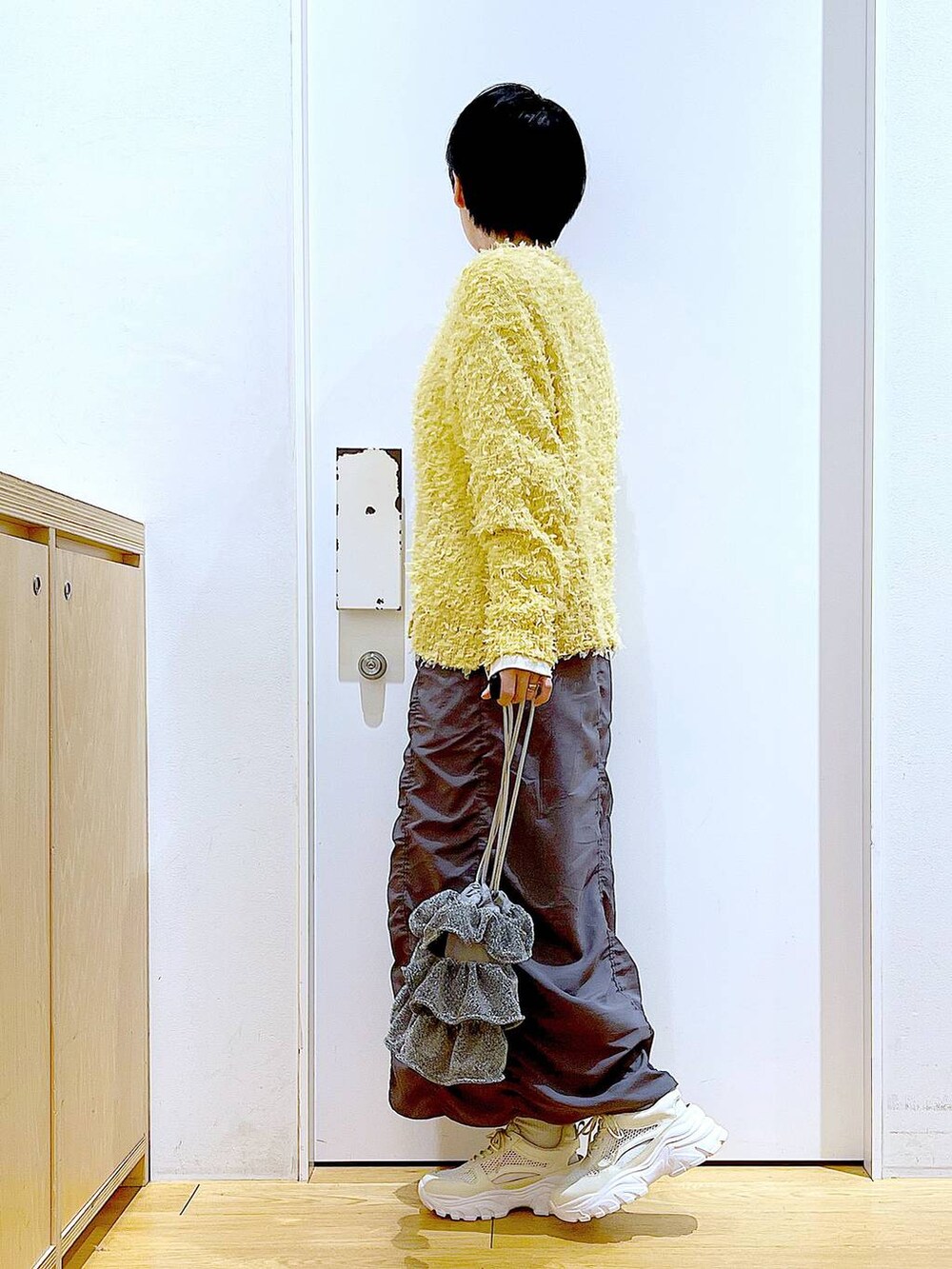 シルバー系のショルダーバッグ、グレー系のスカート、ホワイト系のスニーカーを着用したレディースの春コーディネートの3枚目の写真