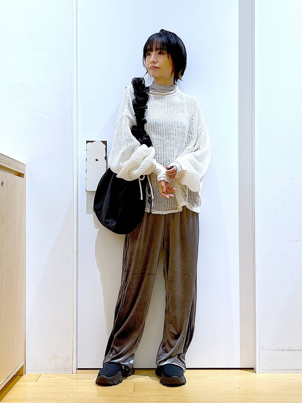 ブラック系のショルダーバッグ、ブラック系のブーツ、ホワイト系のニット/セーターを着用したレディースの冬コーディネートの2枚目の写真