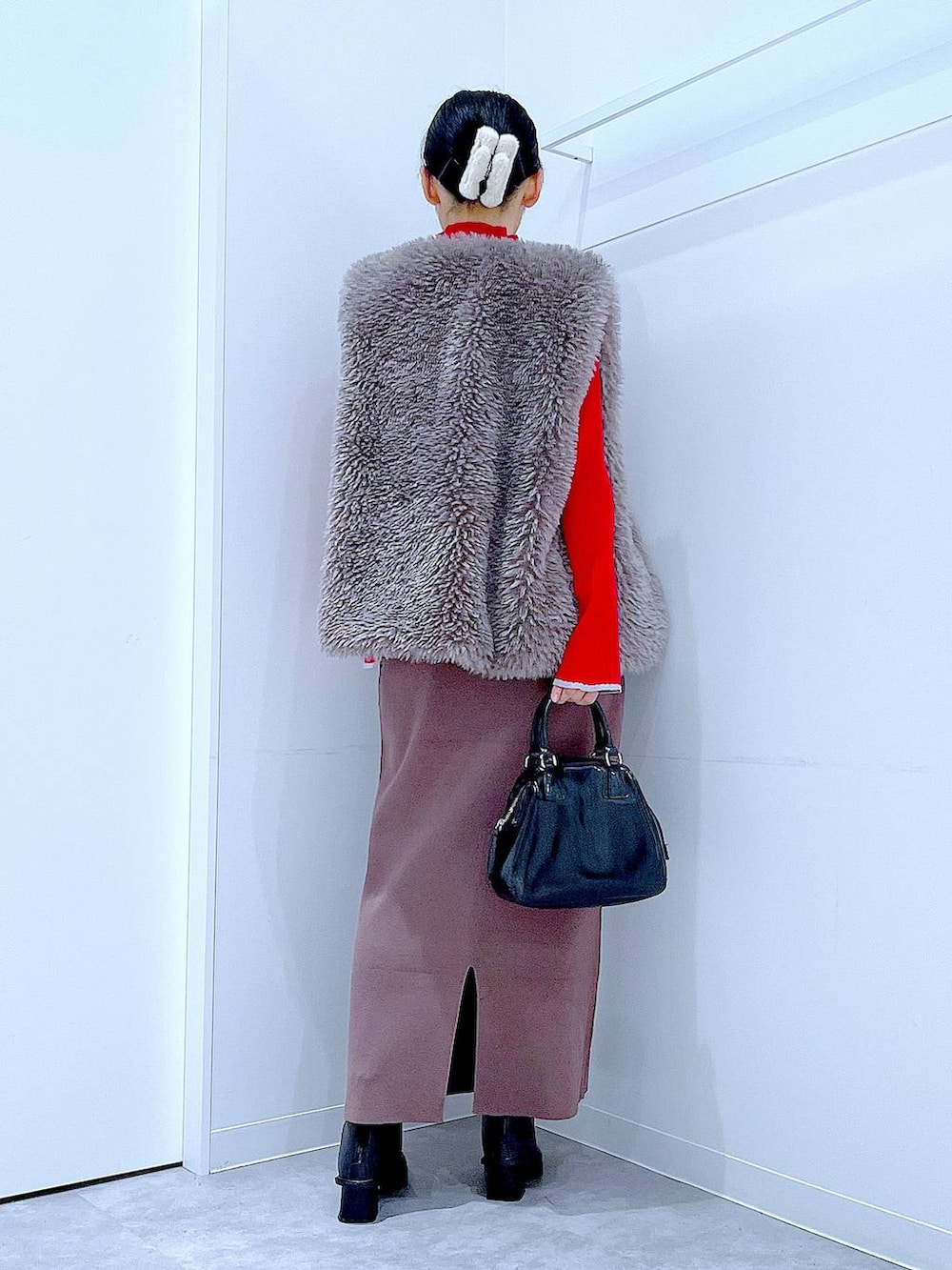 グレー系のベスト、レッド系のニット/セーター、ブラック系のブーツを着用したレディースの冬コーディネートの5枚目の写真