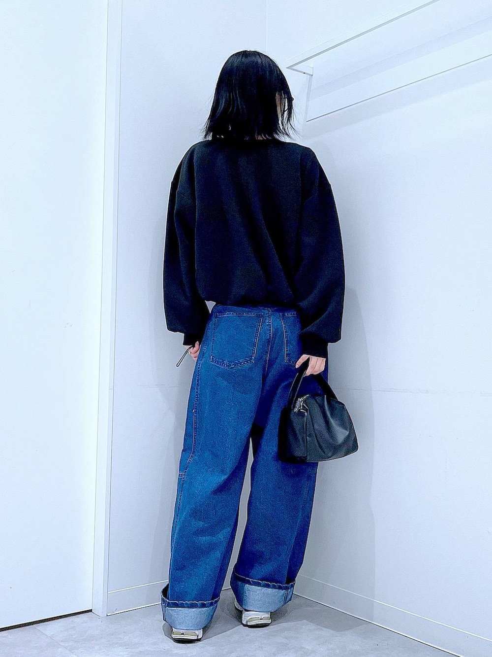 ブラック系のショルダーバッグ、ブルー系のデニムパンツ、ブラック系のスウェットを着用したレディースの春コーディネートの5枚目の写真