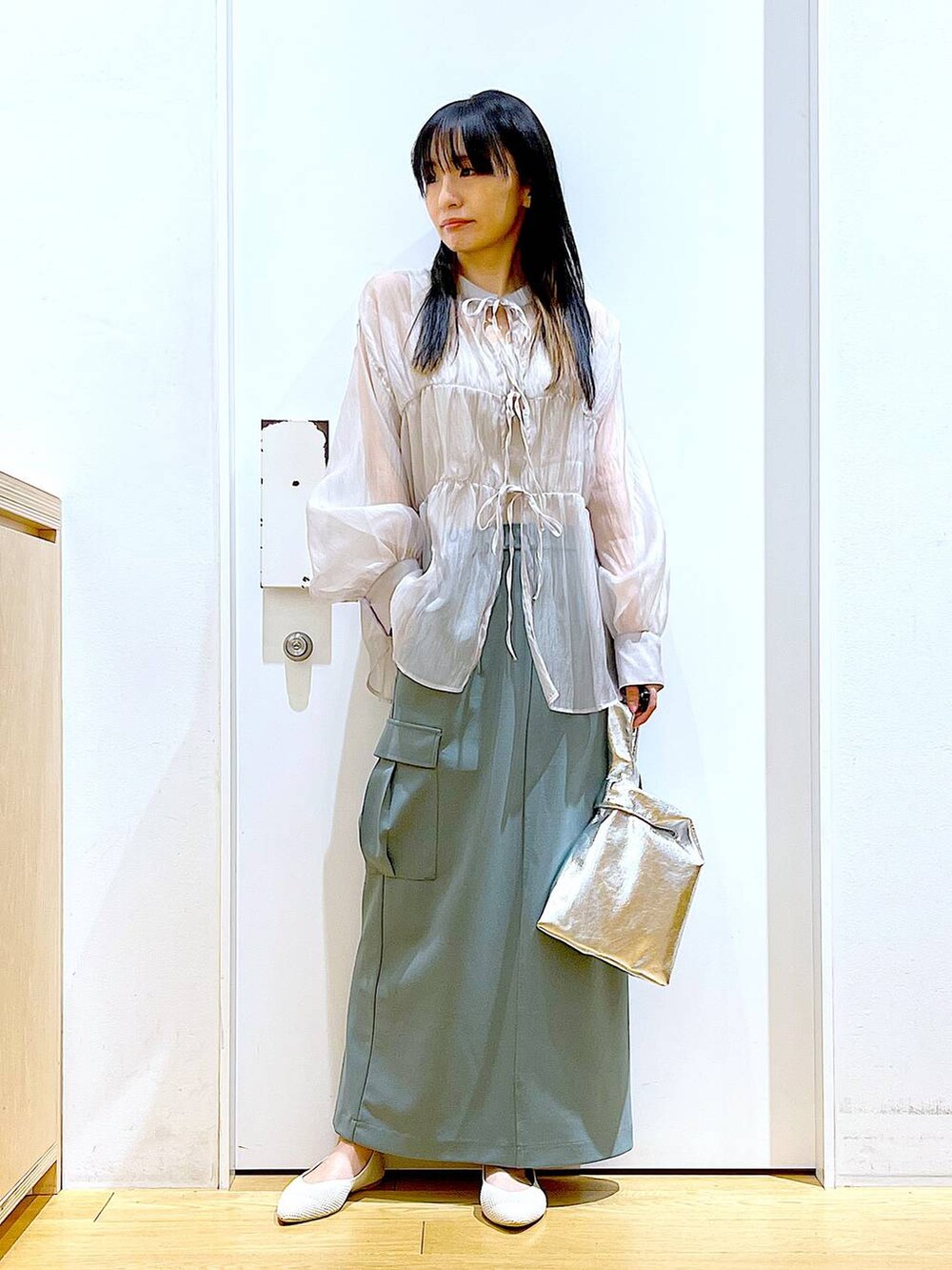 シルバー系のショルダーバッグ、グレー系のシャツ/ブラウス、ホワイト系のパンプスを着用したレディースの春コーディネートの2枚目の写真