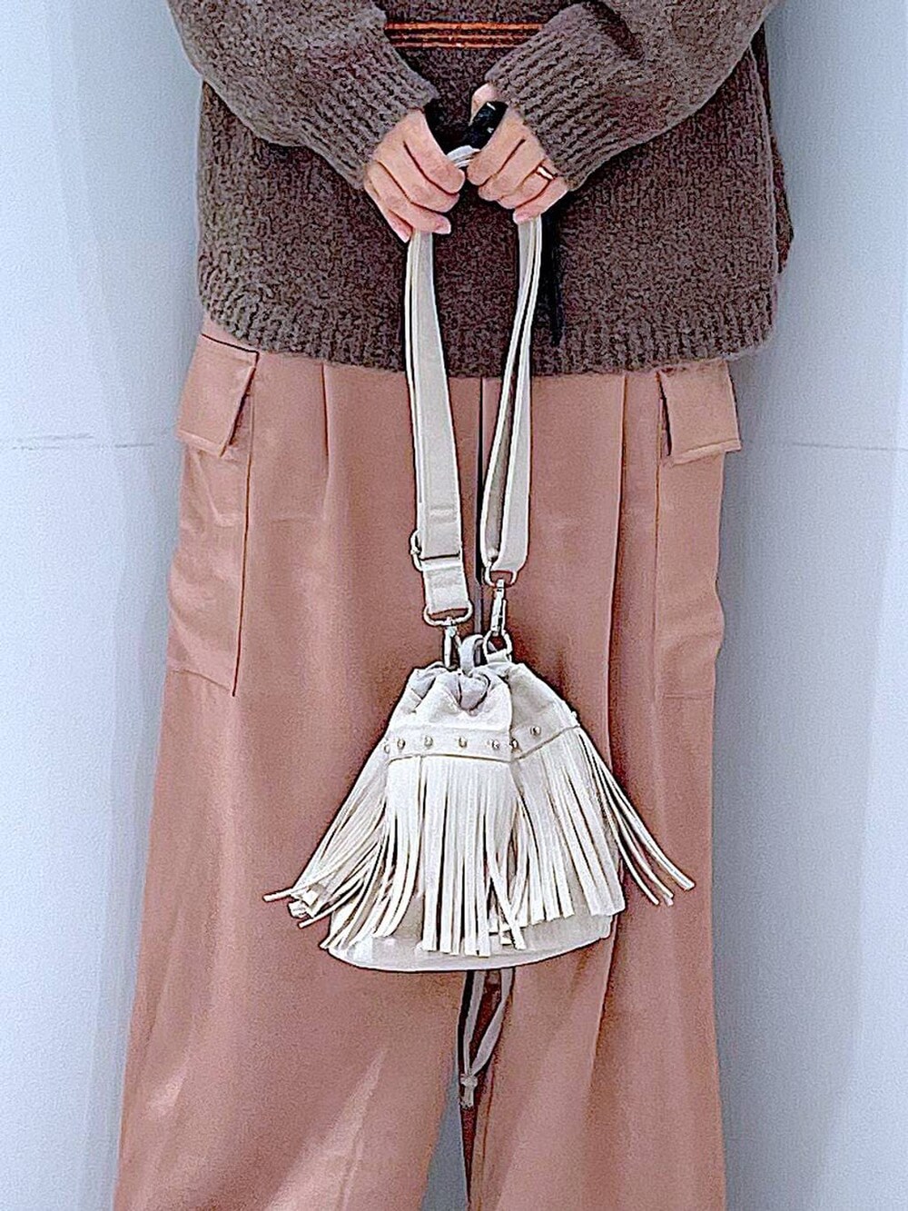 ブラウン系のニット/セーター、ブラック系のブーツ、ホワイト系のショルダーバッグを着用したレディースの冬コーディネートの9枚目の写真