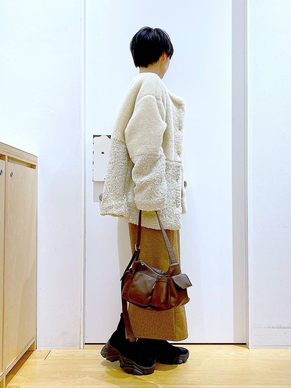 ベージュ系のブルゾン、ブラック系のブーツ、ブラウン系のショルダーバッグを着用したレディースの冬コーディネートの4枚目の写真