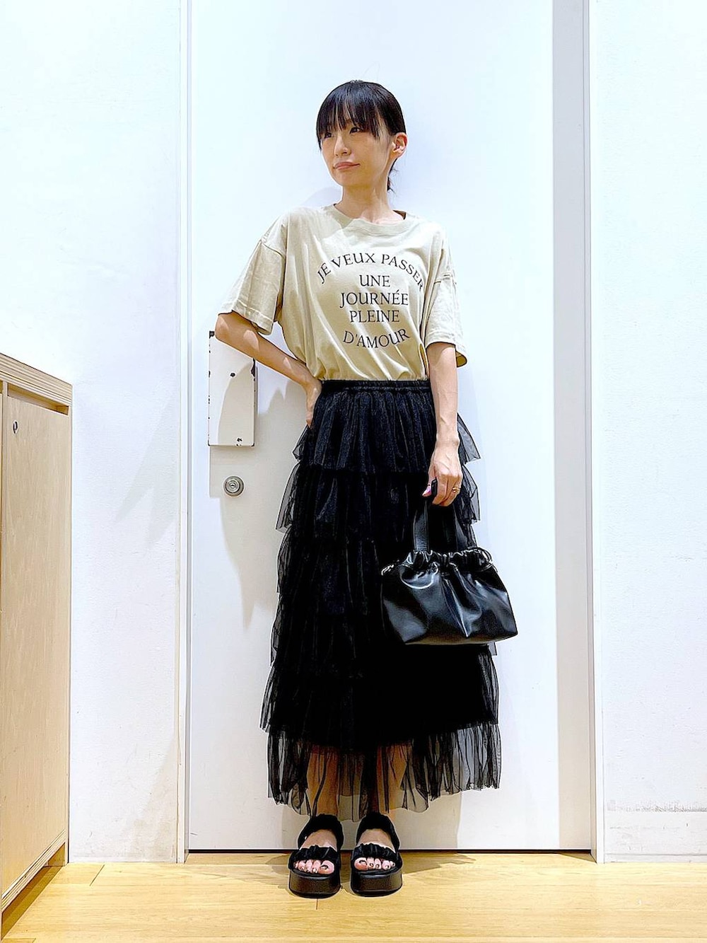 ブラック系のサンダル、ブラック系のショルダーバッグ、ブラック系のスカートを着用したレディースの夏コーディネートの2枚目の写真