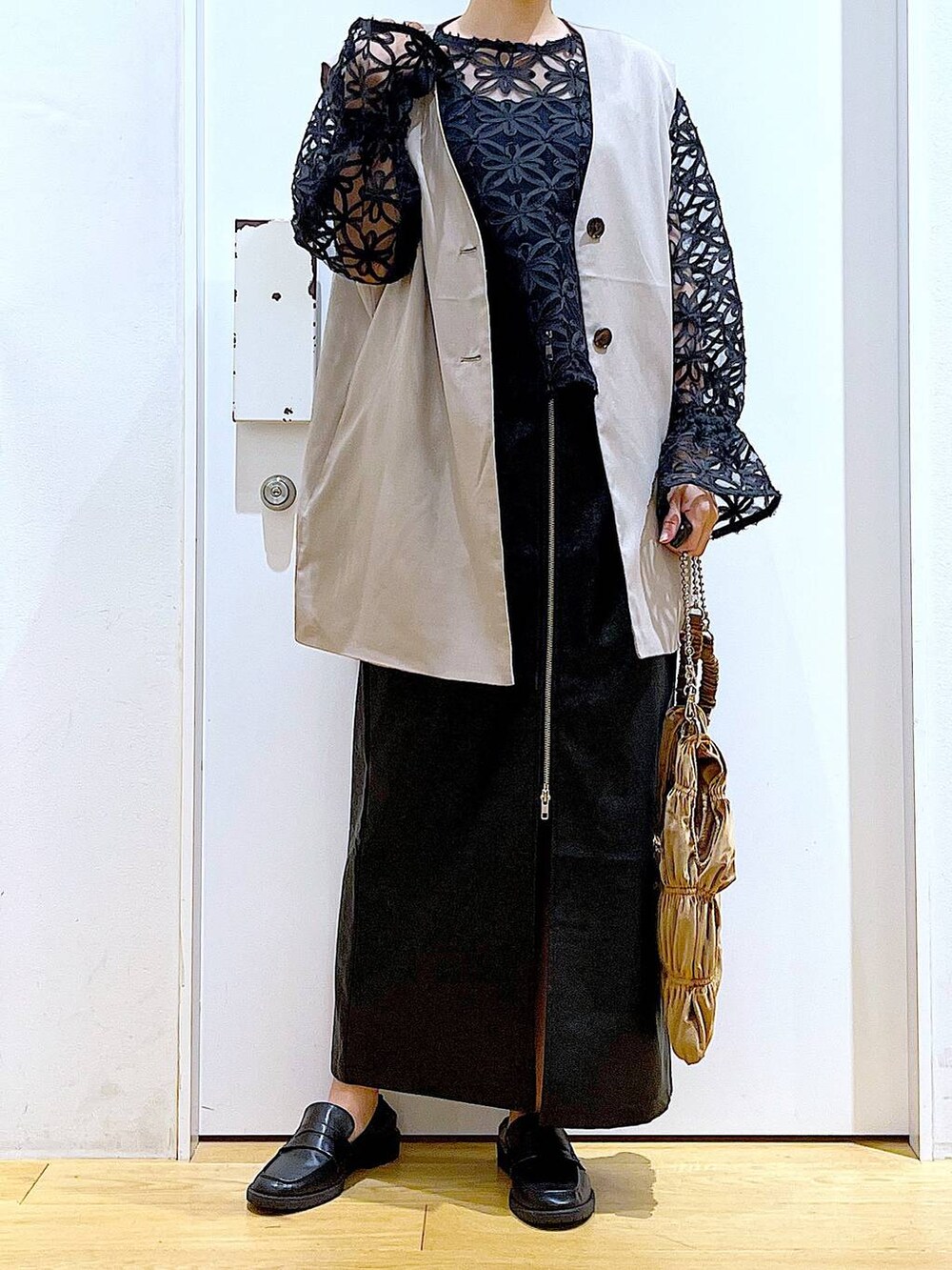 ブラック系のスカート、ブラック系のローファー、ベージュ系のベストを着用したレディースの秋コーディネートの6枚目の写真