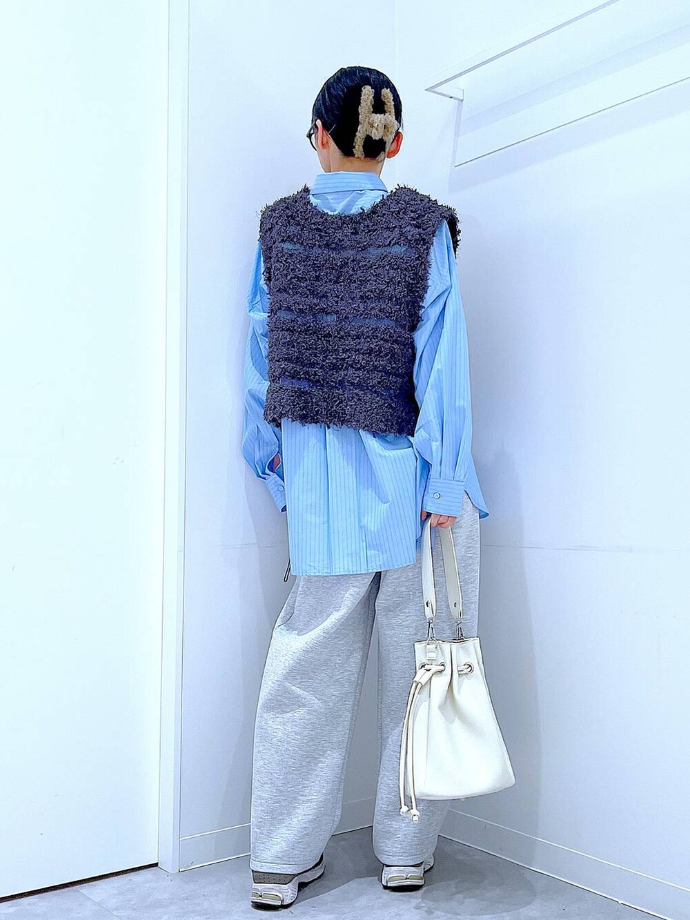 ブルー系のシャツ/ブラウス、ホワイト系のショルダーバッグ、グレー系のベストを着用したレディースの春コーディネートの5枚目の写真