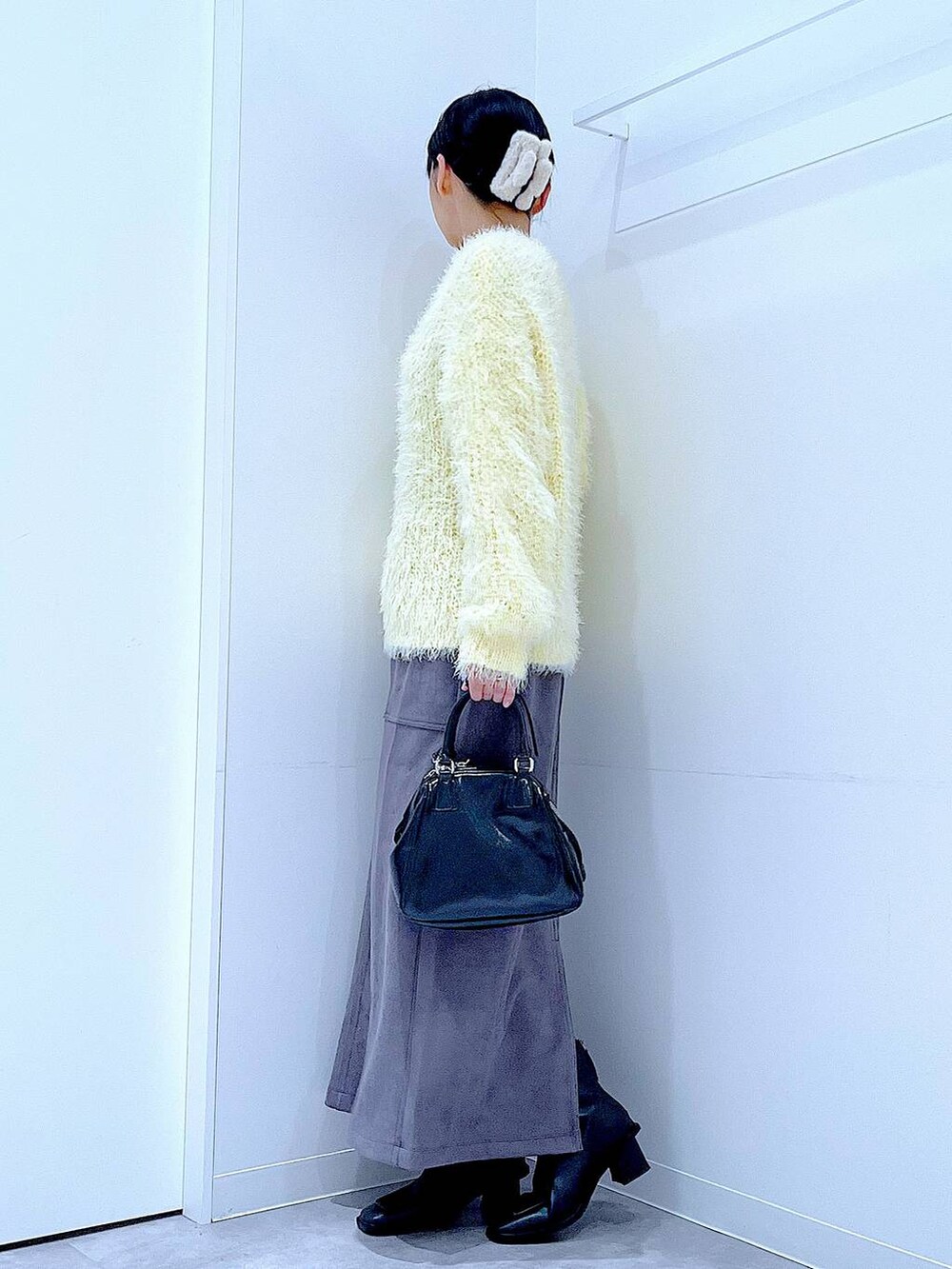 ブラック系のブーツ、イエロー系のニット/セーター、ブラック系のショルダーバッグを着用したレディースの冬コーディネートの3枚目の写真