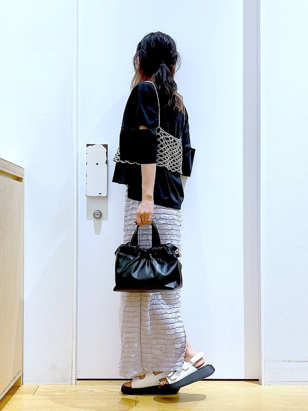 ホワイト系のサンダル、ブラック系のショルダーバッグ、シルバー系のベストを着用したレディースの夏コーディネートの3枚目の写真