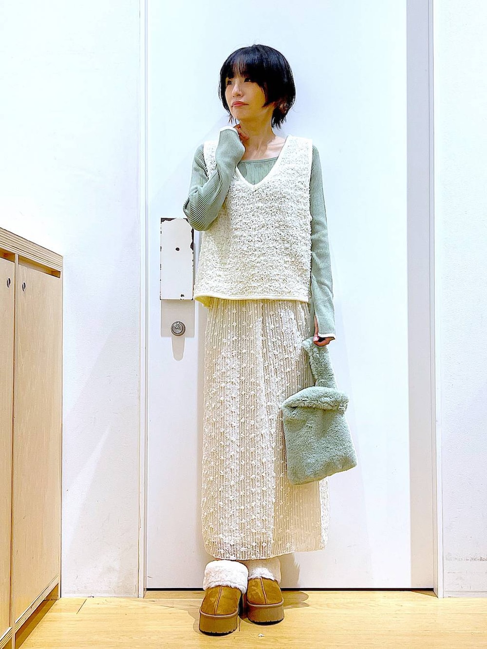 グリーン系のニット/セーター、グリーン系のショルダーバッグ、ベージュ系のベストを着用したレディースの秋コーディネートの2枚目の写真