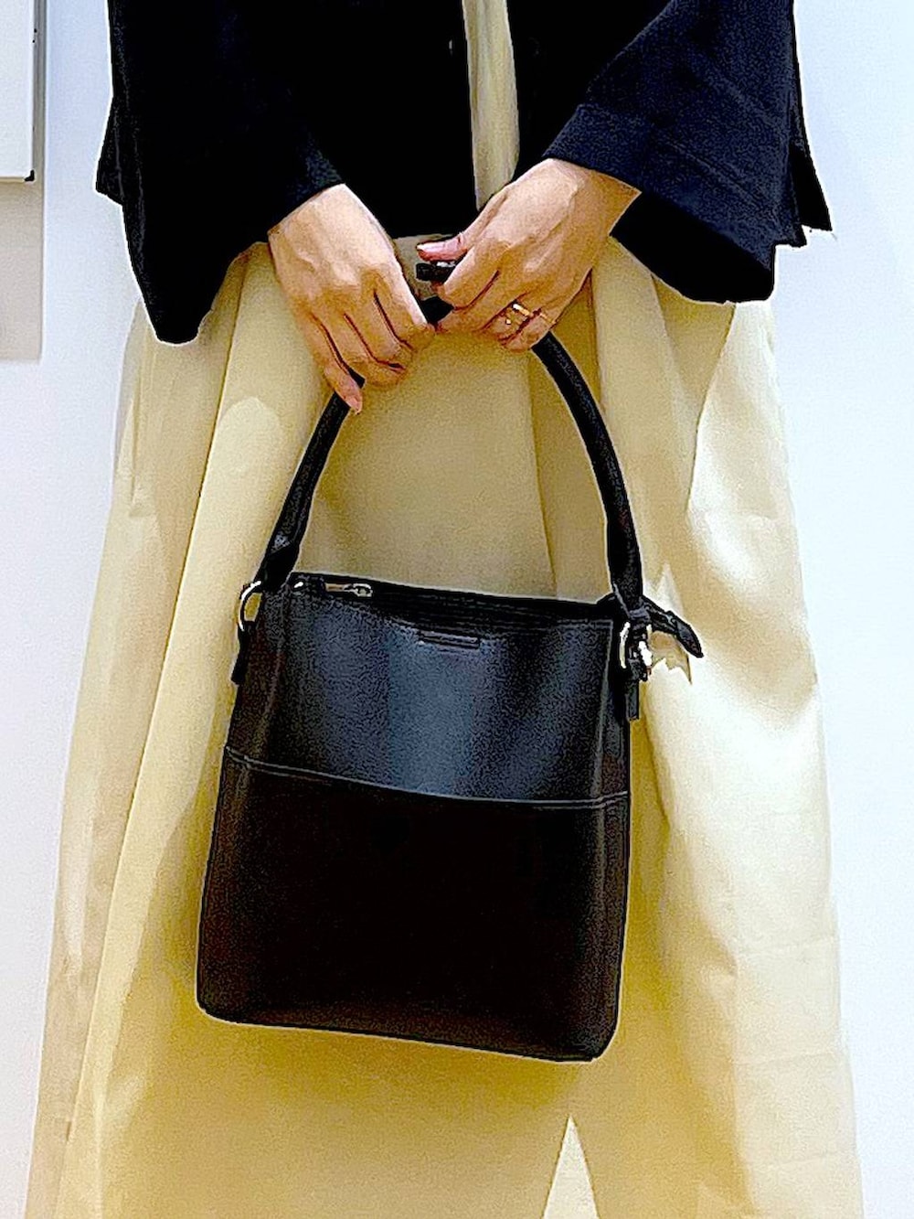 イエロー系のワンピース、ブラック系のショルダーバッグ、ブラック系のパンプスを着用したレディースの秋コーディネートの9枚目の写真