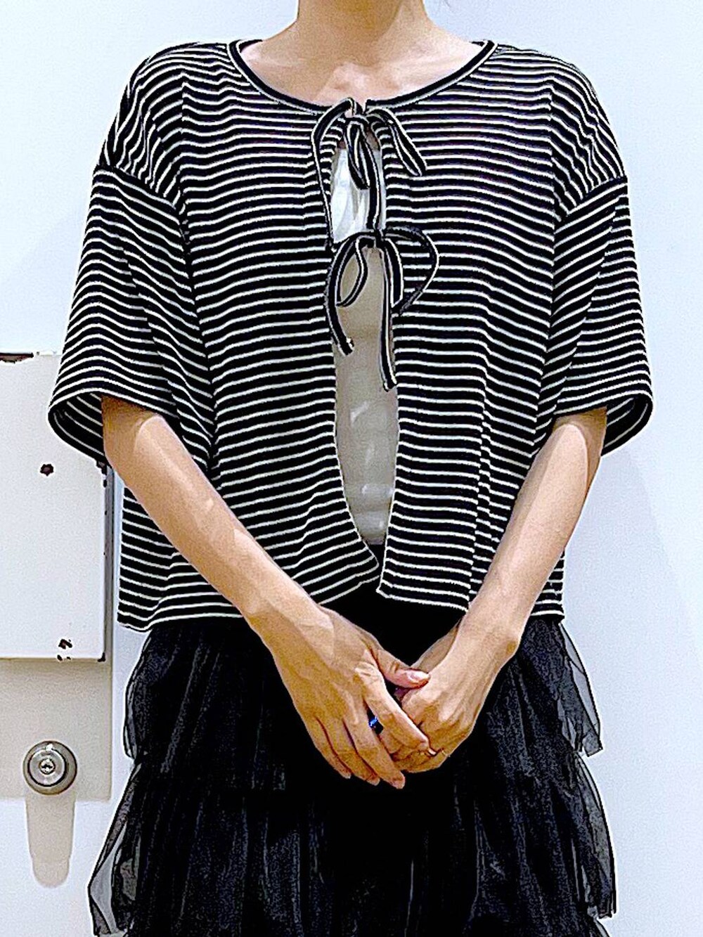 ホワイト系のサンダル、ホワイト系のショルダーバッグ、ブラック系のスカートを着用したレディースの夏コーディネートの7枚目の写真