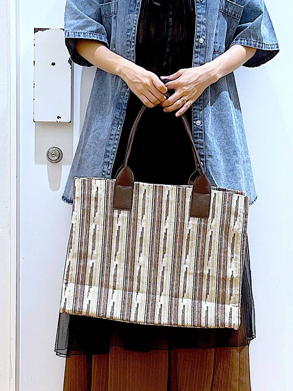 ブラック系のサンダル、ブラウン系のトートバッグ、ブラック系のワンピースを着用したレディースの夏コーディネートの9枚目の写真