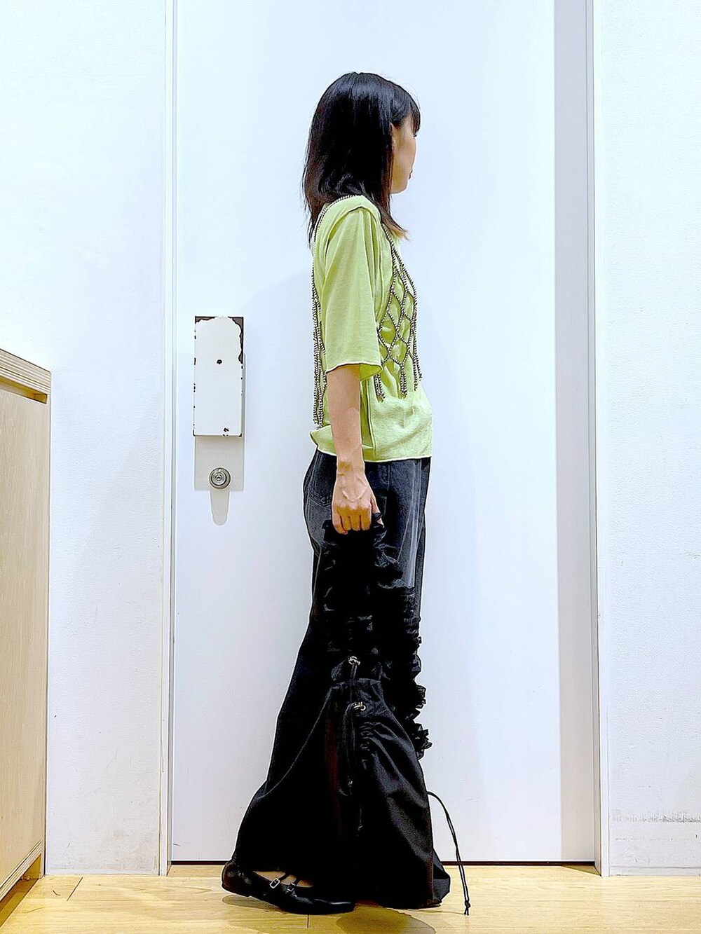 グリーン系のTシャツ/カットソー、ブラック系のデニムパンツ、ブラック系のパンプスを着用したレディースの秋コーディネートの4枚目の写真