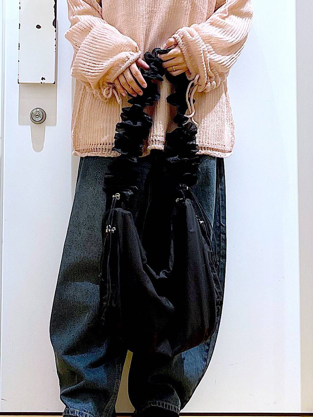 ブラック系のショルダーバッグ、ブラック系のブーツ、ピンク系のニット/セーターを着用したレディースの冬コーディネートの9枚目の写真