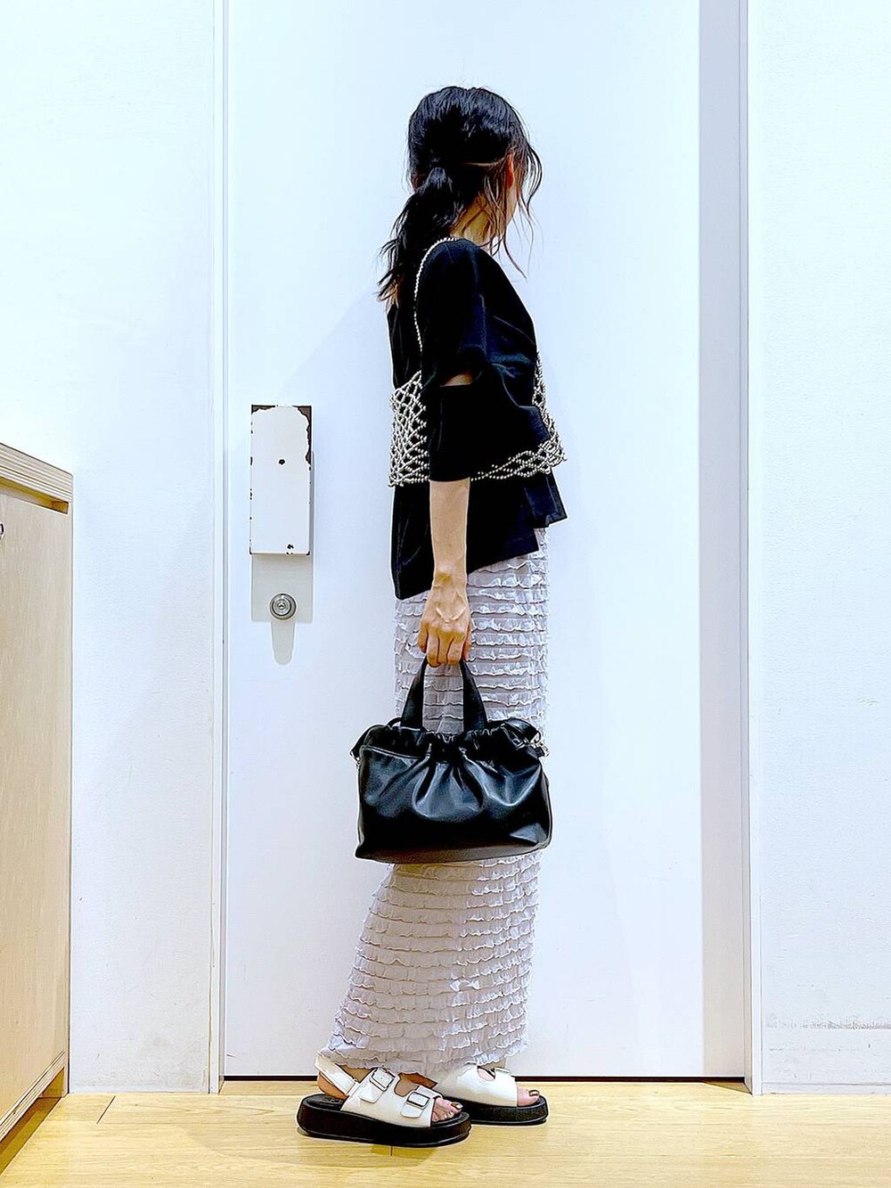 ホワイト系のサンダル、ブラック系のショルダーバッグ、シルバー系のベストを着用したレディースの夏コーディネートの4枚目の写真