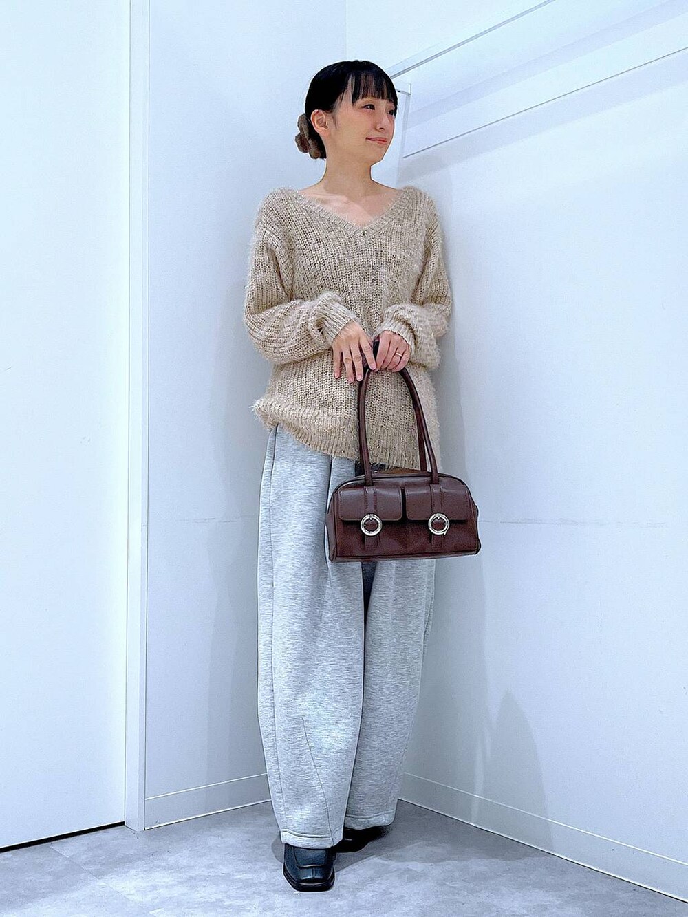 ブラウン系のショルダーバッグ、ブラック系のブーツ、グレー系のスウェットパンツを着用したレディースの冬コーディネートの2枚目の写真